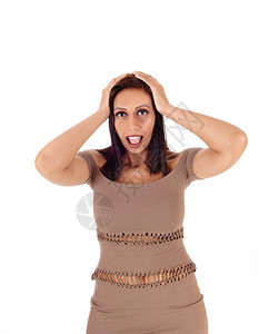 一位美丽的年轻瘦女人穿着棕色短裙双手戴在头上吓人与白背景隔绝图片