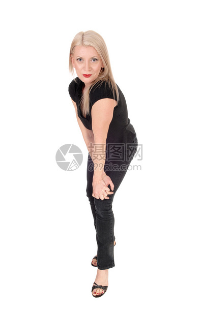 一个笑的中年金发女人站在侧面弯着手的膝盖与白种背景隔绝图片
