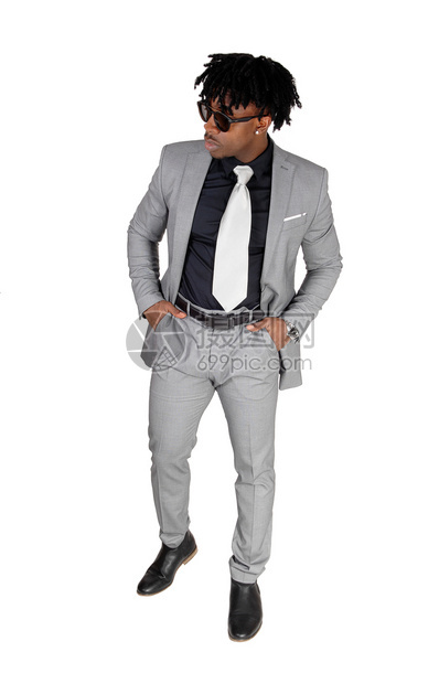 一名身着灰色西装的非裔美国青年男子身着太阳眼镜手放在口袋里为白背景被孤立图片