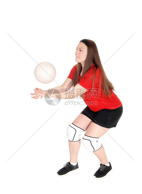 一个穿制服的年轻少女穿着制服玩排球试图用手抓住球与白种背景隔绝图片