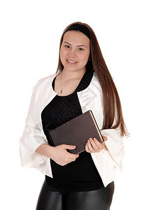 一个美丽的年轻女孩穿着黑皮短裤站在手里拿着一本书笑与白背景隔绝图片