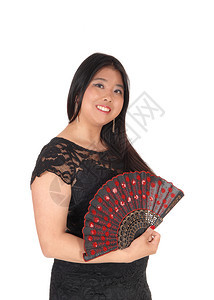 一位美丽的亚洲女穿着黑色裙子站在一副形象中手握着她漂亮的风扇与白种背景隔绝图片