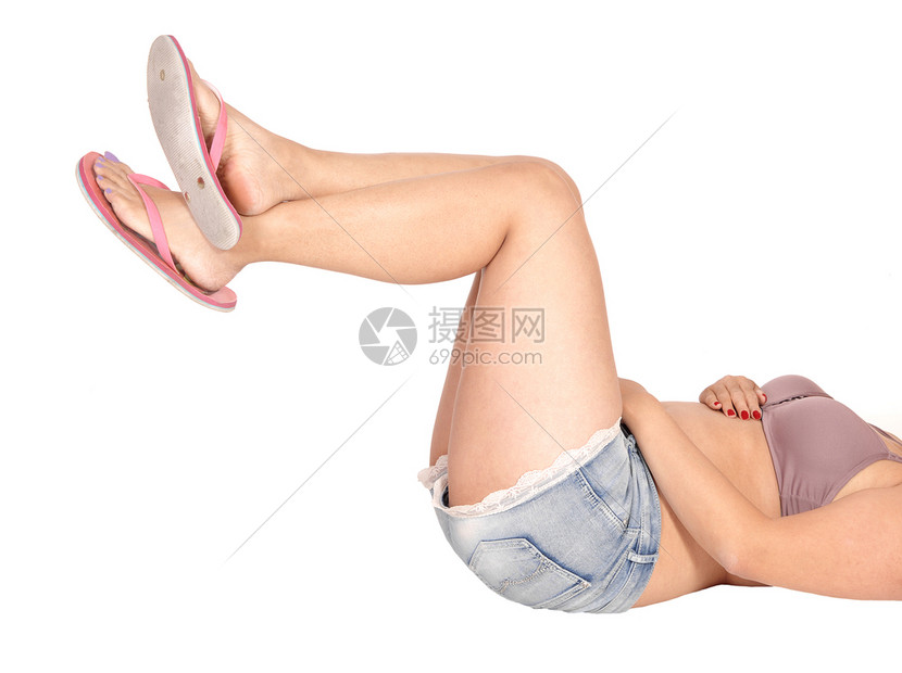 紧贴着一个亚洲女人的腿和臀部图像她躺在地板上双腿抬起来为白色背景而隔离图片