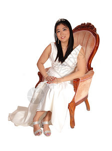 一位美丽的年轻新娘穿着白色婚纱坐在旧时装椅子上与白色背景隔绝图片