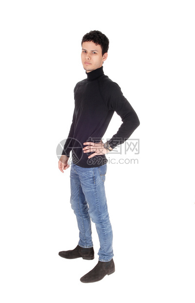 一个穿着黑色毛衣和牛仔裤的帅年轻男子站在工作室休息和微笑与白背景隔绝图片