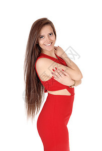 一个美丽的瘦年轻女人穿着红色紧身礼服站在她长的棕发笑着与白背景隔绝图片