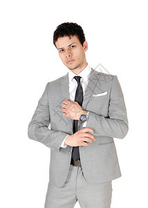 一个年轻英俊的商人站在工作室穿着浅灰色西装思考看着镜头图片