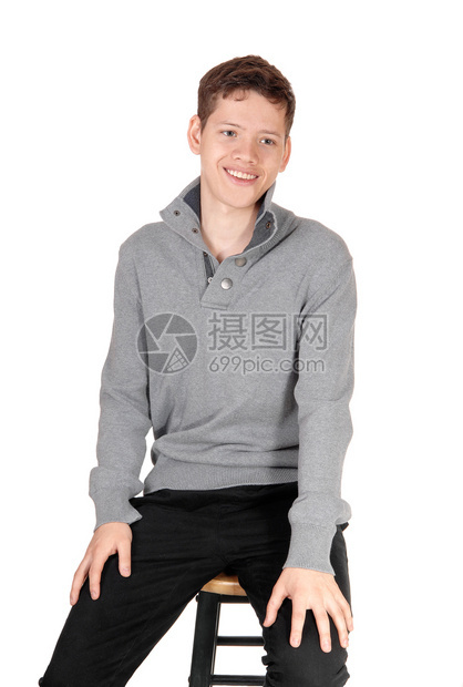 一个笑的年轻英俊少男孩穿着灰色毛衣坐在椅子上图片