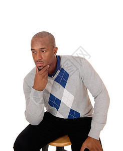 一个年轻英俊的非裔美国人男子坐在工作室的腰部上一只手在下巴上思考孤立于白种背景图片