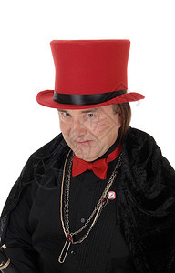 一个穿着黑色衣服的严肃魔术师和一顶红色帽子拿着领带和珠宝商看着相机与白色背景隔绝图片