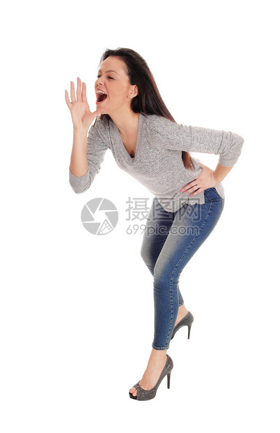 一只瘦的年轻女人站着弯腰一只手放在嘴上向人大喊叫与白种背景隔绝图片