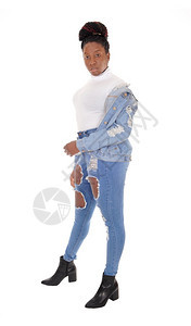 一个年轻的非裔美国妇女穿着破牛仔裤外套站在肩上白顶图片