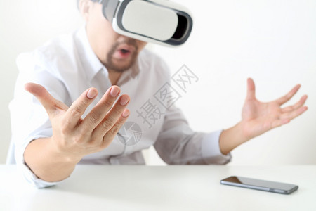 商人在现代办公室佩戴虚拟现实护目镜用手机VR头戴VR盔图片