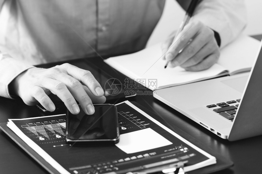 在现代办公室黑人和白办公室的木制桌上使用智能电话数字平板脑和笔记本图片