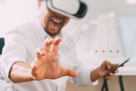 商人在现代办公室佩戴虚拟现实护目镜用手机VR头戴VR盔图片