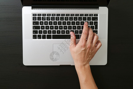在现代办公室黑色和白的木制办公桌上用笔记本电脑打键盘图片