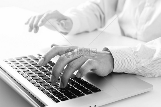 在现代办公室黑白的色桌上黑白室用笔记本电脑打键盘图片