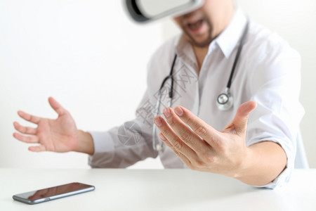 身戴虚拟现实镜的智能医生在现代办公室使用手机VR头盔的现代办公室使用手机图片