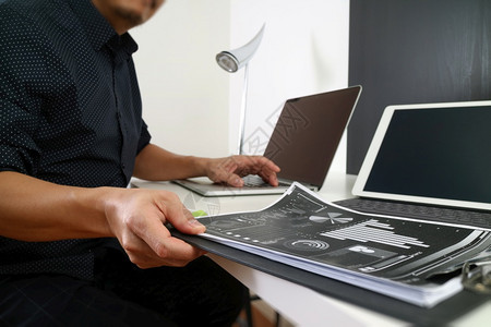 在现代办公室使用智能电话数字平板脑和笔记本文件的商人图片