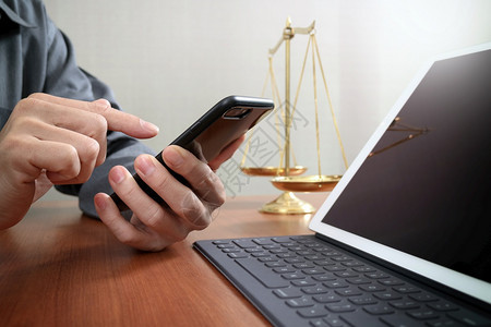 平衡的黄铜比例在职男律师用智能电话和数字平板脑在木制桌子上工作图片