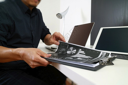 在现代办公室使用智能电话数字平板脑和笔记本文件的商人图片