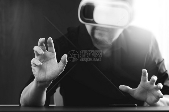 商人在现代办公室戴虚拟现实镜用手机使VR头盔黑白图片