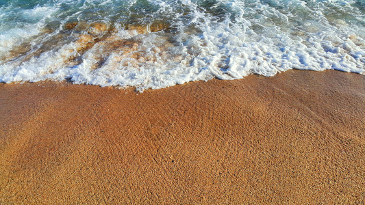 海浪沙滩上有白泡沫自然背景图片