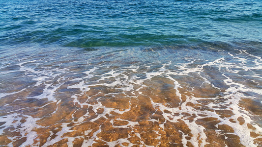 沿海沙砂中带白泡沫的清海水天然封闭背景图片