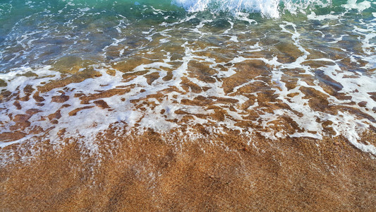 沿海沙砂中带白泡沫的清海水天然封闭背景高清图片