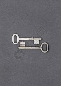 两个旧的简单金属钥匙灰纸背景的旧金属钥匙特写图片
