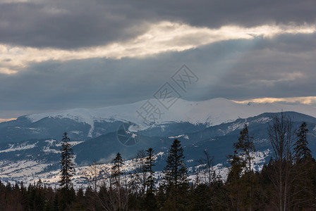 冬雪覆盖的山脊和来自云层覆盖的天空乌克兰喀尔巴阡山斯维多脉的阳光图片