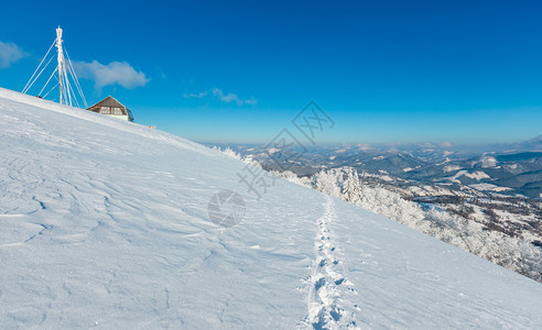 美丽的冬季红霜树通讯塔和人行道穿过蓝天空背景的山坡上雪田喀尔巴阡山乌克兰图片