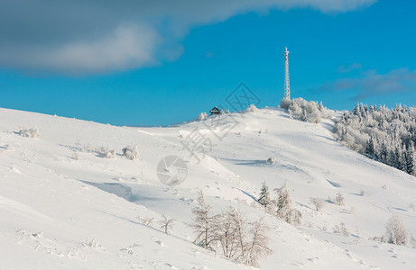美丽的冬季霜树通讯塔和山顶上蓝色云雾天空背景的雪地滑喀尔巴阡山乌克兰图片
