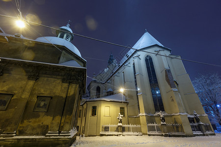 乌克兰利沃夫市罗马天主教大管区Basilica和博伊姆教堂美丽的雪之夜严寒冬城景有照明弹可用背景图片