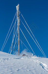 美丽的冬季红糖霜通讯塔和山顶的雪地漂浮在蓝天空背景的山顶上综合图像具有相当深的田野锐利度图片