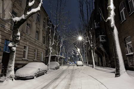 乌克兰利沃夫市中心美丽的黄昏冬季城市景观汽车被雪覆盖了图片