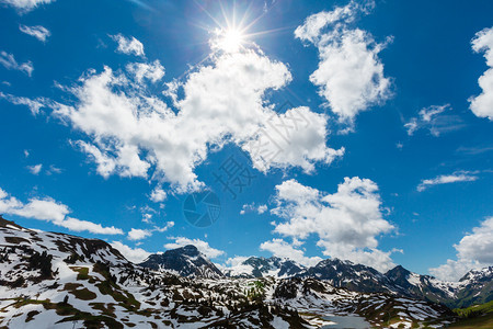 阿尔卑斯山脉从霍赫坦贝山口的春日光下看山景蓝色天空有太阳和云沃斯拉尔贝格奥地利有一些太阳耀斑效应图片
