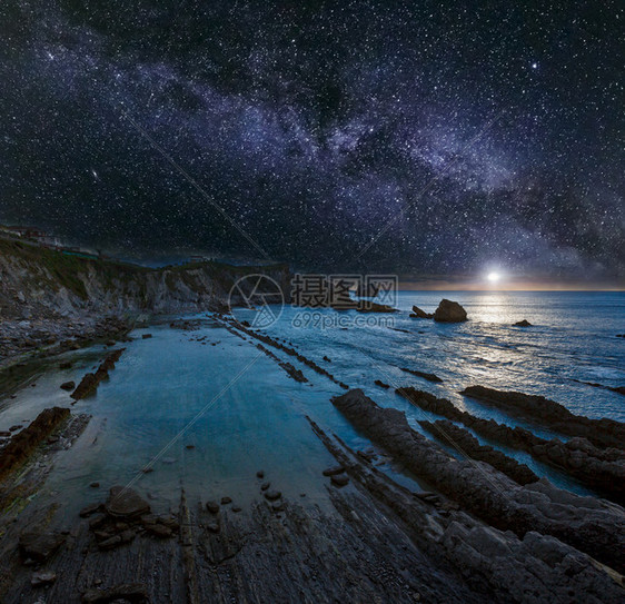 ArniaBeach西班牙大洋沿岸从岩石中夜视月亮和星状银河在天空中升起月光在水中反射图片