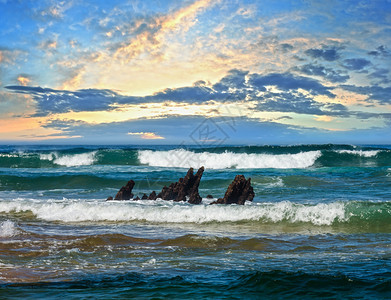 海浪和小岩石在中央晚上日落海景从滩看图片