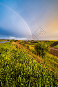 春种和小农田在雨夜风景阴云的日落天空彩虹多和农村山丘之后出现自然季节天气候农业村美貌概念图片