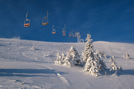 阿尔卑斯山度假胜地滑雪电梯座椅穿过日出山顶滑雪自由坡和fir树林图片