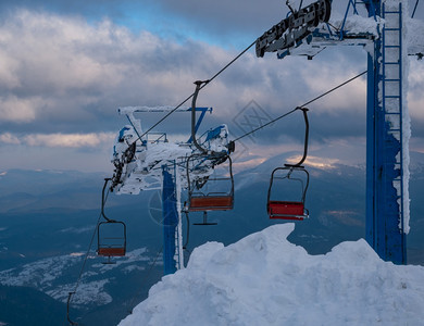 高山度假胜地滑雪电梯在极风天气下座椅穿过日落的山坡滑雪图片