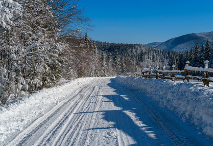 通往边远山区小村庄高的二级公路穿过雪林流和路边的木栅栏图片