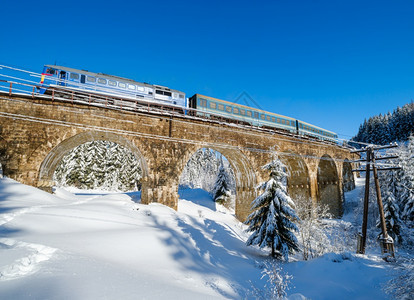 在山雪森林的铁路上建造石桥archbridge雪漂在路边树木和电线上漂浮图片