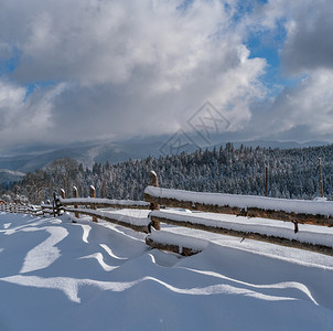 阿尔卑斯山冬村郊区雪道遥远的迷雾和多云山丘上森林图片