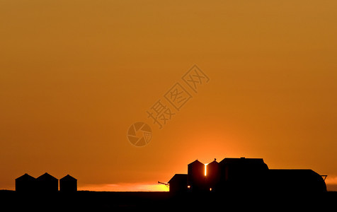 日落的萨斯喀彻温橙色天空和农场建筑图片