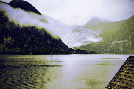 奥地利Hallstattersee的雨和云清晨的雾散落在奥地利的风景上有湖森林田地牧场草和瓷砖屋顶图片