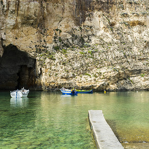 在由纯石灰岩悬崖划定的崎岖海岸线上游艇充满了马耳他的深洞内海是戈佐岛与地中海相连的环礁湖由狭窄的自然拱门形成图片