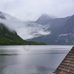 奥地利Hallstattersee的雨和云层早上在奥地利的貌上喷雾湖森林农田牧场草原和瓷砖屋顶图片