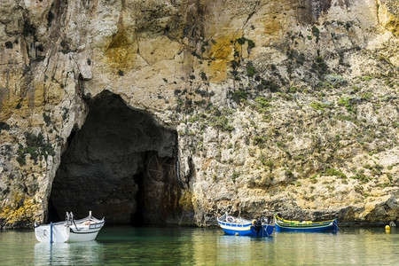 在由纯石灰岩悬崖划定的崎岖海岸线上游艇充满了马耳他的深洞内海是戈佐岛与地中海相连的环礁湖由狭窄的自然拱门形成图片
